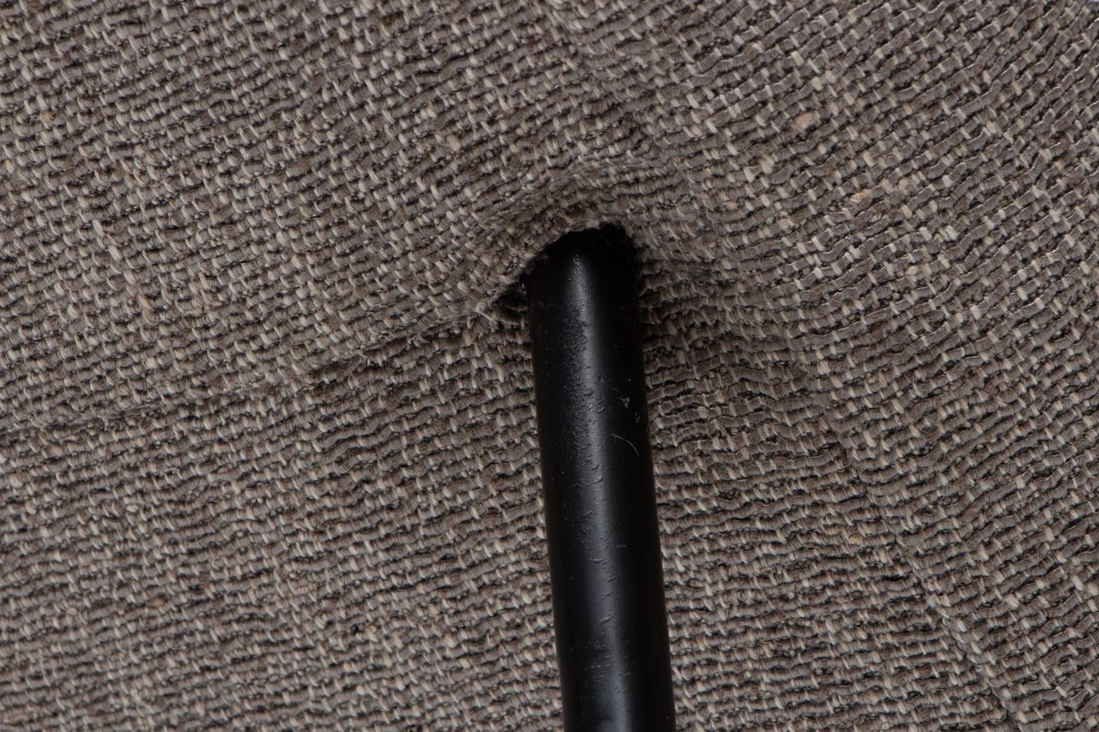 Gros plan sur le tissu chiné gris et sur un pied en métal noir qui traverse la garniture