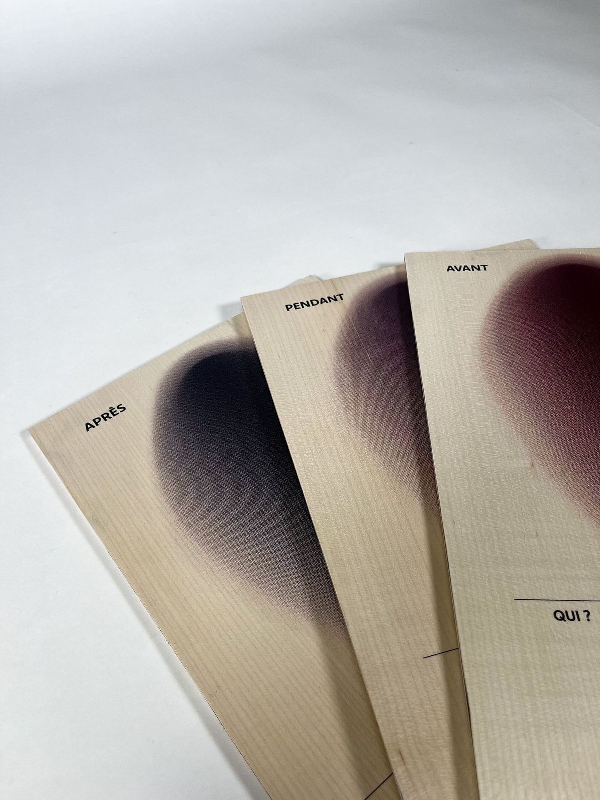 Trois planches en bois « Après », « Pendant » et « Avant » posées en éventail, chacune marquée d’une tache de couleur allant du noir au bordeaux