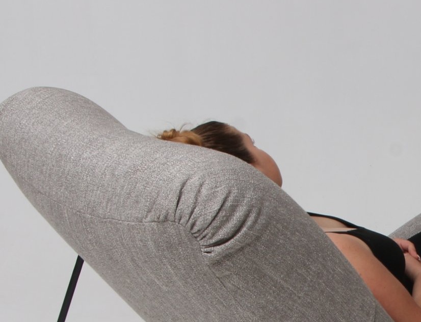 Gros plan sur un fauteuil rembourré en tissu gris chiné, avec une personne allongée dedans